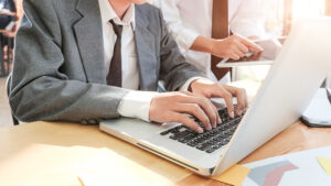 Seorang pebisnis sedang mencari informasi antara website dan blog di depan laptop.