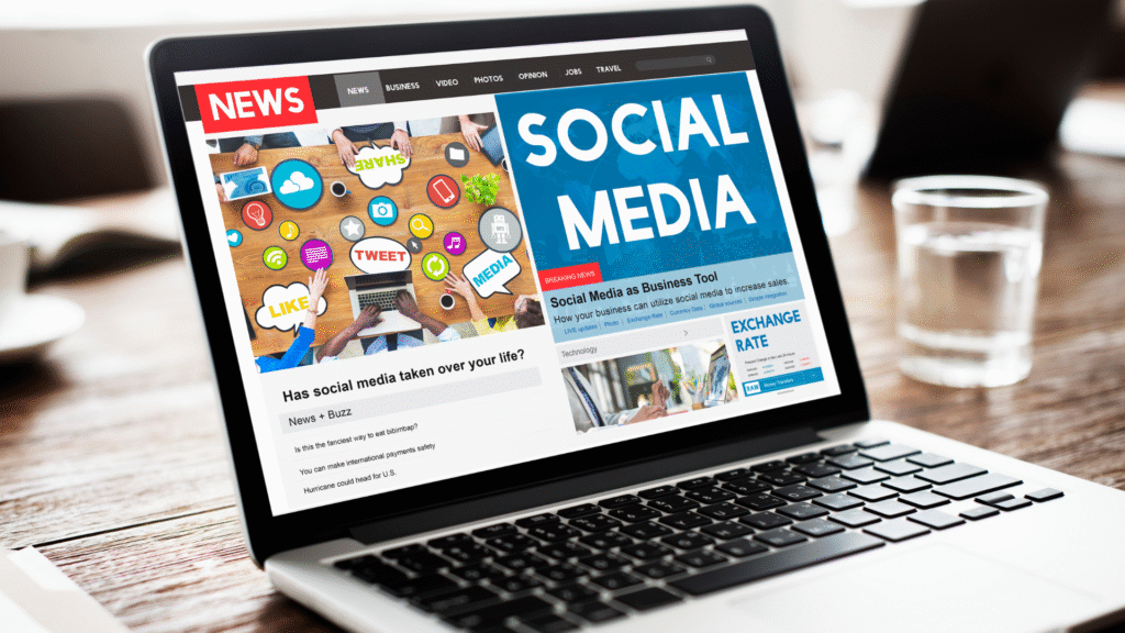 Tampilan layar laptop menampilkan halaman berita online bertema "Social Media" dan artikel terkait penggunaan media sosial dalam bisnis.