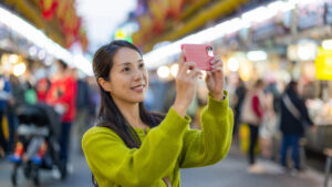 Seseorang membuat User Generated Content dengan merekam video menggunakan handphone untuk strategi pemasaran media sosial bisnis.