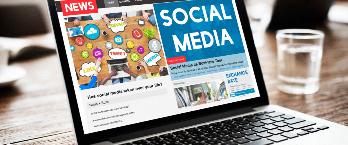 Tampilan layar laptop menampilkan halaman berita online bertema "Social Media" dan artikel terkait penggunaan media sosial dalam bisnis 