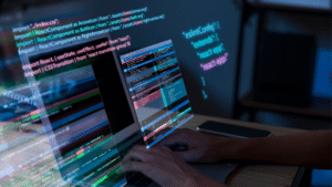 Seorang developer sedang menulis kode pemrograman menggunakan ReactJS pada laptop dengan tampilan antarmuka modern dan visualisasi kode berwarna.