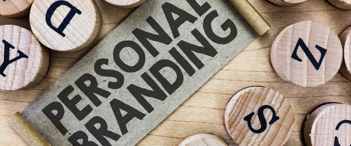 Teks "Personal Branding" tercetak tebal di atas gulungan kertas coklat, dikelilingi keping kayu bertuliskan huruf huruf alfabet, menggambarkan konsep identitas dan komunikasi personal 