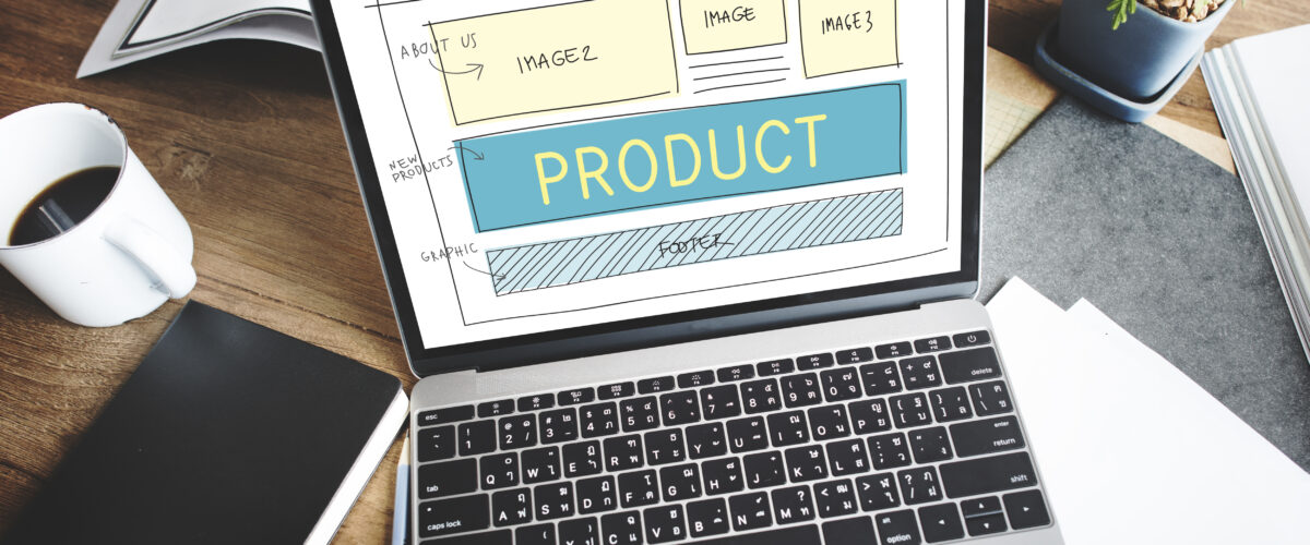 Sketsa desain tampilan website produk pada layar laptop di atas meja kerja 