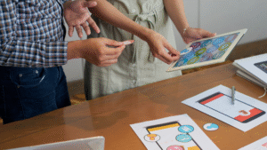 Dua orang mendiskusikan elemen desain antarmuka pengguna (UI) website menggunakan tablet dan mockup, merepresentasikan proses branding digital. Dua orang mendiskusikan elemen desain antarmuka pengguna (UI) website menggunakan tablet dan mockup, merepresentasikan proses branding digital.